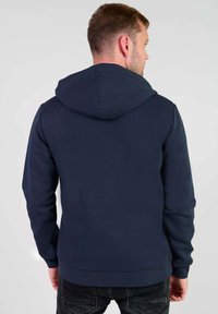 Sudadera con capucha en navy, con una textura suave, mangas largas y puños de canalé. Presenta un bolsillo tipo canguro y un diseño de canesú en la parte posterior.