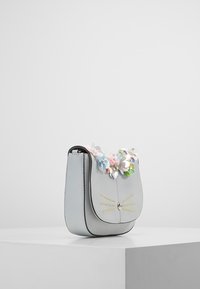 Světlá šedá kožená kabelka s zakřivenou klopou, zdobená barevnými květinovými akcenty a žlutým prošíváním připomínajícím vousky.