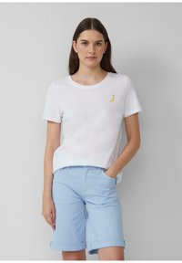 Witte t-shirt met korte mouwen en een klein geel geborduurd bananadesign, gecombineerd met lichtblauwe shorts met omgeslagen zoom. Soepele textuur.