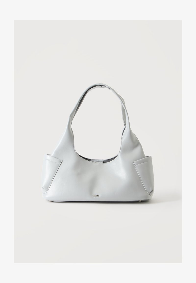 Sac à main en cuir gris clair avec une seule poignée incurvée et de petites poches extérieures de chaque côté sur un fond uni.