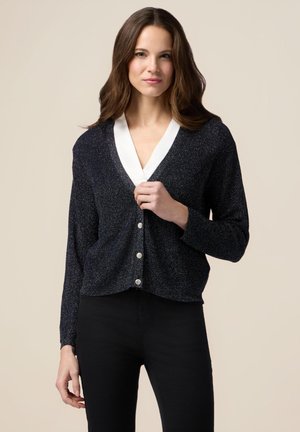 Cardigan blu navy con applicazioni glitterate, colletto a V bianco e chiusura con bottoni argentati. Maniche lunghe e texture morbida completano un look casual.