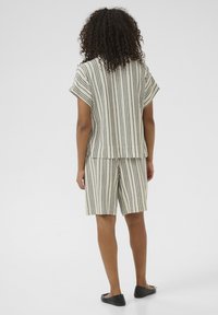 Ensemble de haut à manches courtes rayé et de shorts en beige avec des rayures verticales noires. Tissu doux ; coupe décontractée avec une silhouette loose.