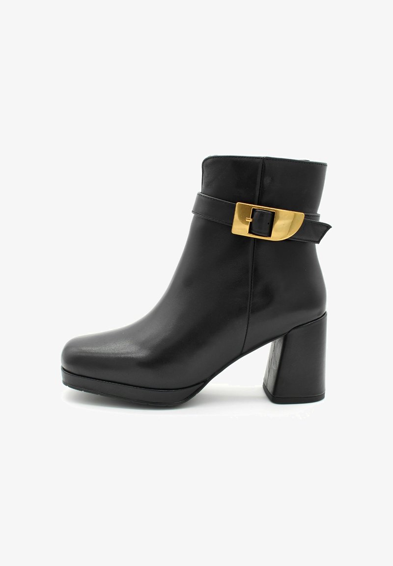 Bottine en cuir noir avec un large bout carré, un talon épais et une sangle latérale avec une boucle dorée. Texture lisse, design élégant.