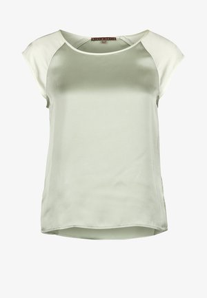 Satynowa zielona bluzka z krótkimi kremowymi rękawami raglanowymi, okrągłym dekoltem i lekko zaokrąglonym dołem. Gładka faktura i swobodny design.