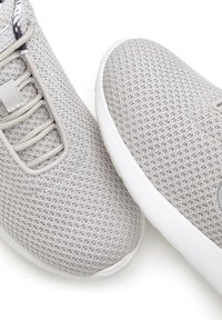 Grey mesh sneakers with a breathable texture, elastic laces, and a white rubber sole. Features a subtle logo on the side.