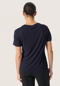 T-shirt blu navy a maniche corte con scollatura rotonda, texture liscia e design aderente, che mostra una leggera caduta sul retro.