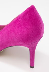 Chaussure à talon haut pour femme en daim rose, bout amande, talon moyen et fin, gros plan sur le talon et la partie arrière.