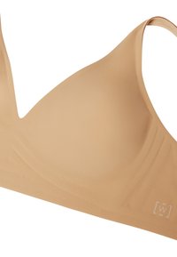 Reggiseno senza cuciture in tonalità nuda con design a V, texture liscia e spalline regolabili. Presenta un branding minimale sul lato.