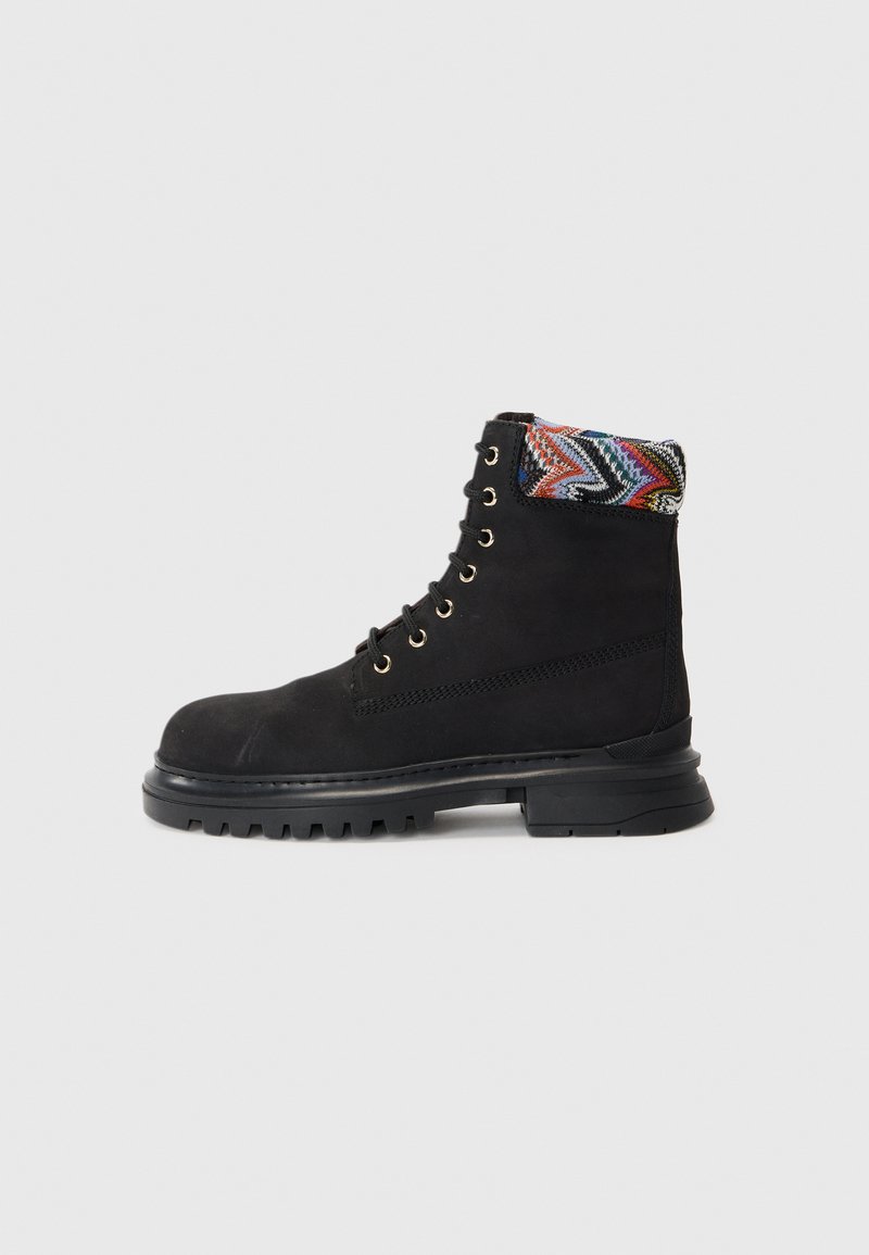 Stivale alla caviglia in suede nero con un bordo a motivi multicolore testurizzati, occhielli in metallo e suola in gomma robusta. Presenta un design con lacci.