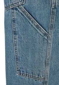 Țesătură de denim albastru deschis care prezintă un buzunar lateral cu cusături vizibile portocalii. Textura este ușor decolorată, având un model uniform.