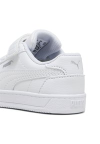 Zapatilla blanca con parte superior de cuero texturizado, cuello acolchado y correa de velcro. Presenta un sutil logo gris y suela de goma con patrón texturizado.