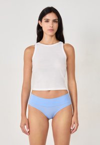 Débardeur en coton blanc avec un col haut et une coupe sans manches, associé à un slip hipster seamless bleu clair, avec un tissu lisse.