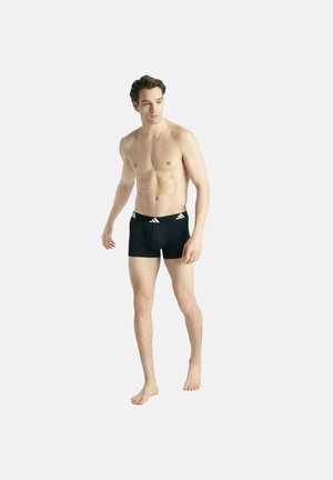 Zwarte sportieve zwembroek met een witte merkband in de taille. De stof lijkt glad, en het ontwerp heeft een aansluitende stijl met een kortere pijp.