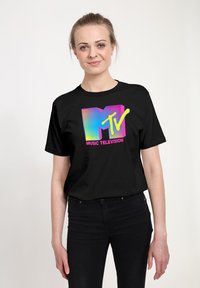 Černé bavlněné tričko se vzhledově atraktivním logem MTV v pestrých barvách s gradientními efekty, prezentované na osobě před neutrálním pozadím.