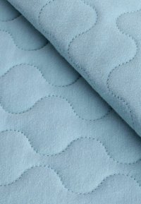 Minkštas mėlynas quilted audinys su banguota raštu ir iškilusiomis siūlėmis, rodančiomis tekstūrą ir gylį. Lygi paviršius su matinio apdaila.