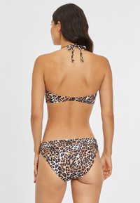 Bikini set s leopardím vzorem obsahující top na zavazování za krk a kalhotky s nízkým pasem, vyrobený z hladké tkaniny. Zadní pohled ukazuje nastavitelné vázání.