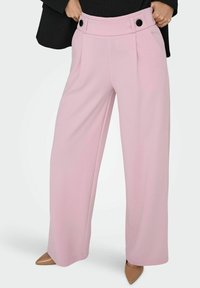 Wide-leg trousers in a soft pink fabric, featuring a high waist with double button detail and front pleats, paired with nude pointed heels.