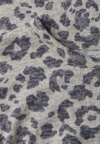Látka s leopardím potiskem v šedých tónech na světle béžovém pozadí. Má kulatý výstřih a je vyrobena z měkké, strukturované bavlny.