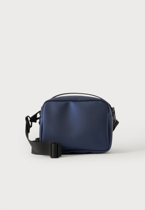 Μικρή ορθογώνια τσάντα crossbody σε ναυτικό μπλε χρώμα με μαύρο ρυθμιζόμενο λουρί, μινιμαλιστικό σχεδιασμό και διακριτικό λογότυπο μπροστά.
