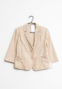 Béžové, lehké sako s klopovým límcem, dvěma knoflíky a dvěma předními kapsami; na límci je připevněna visačka.