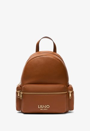 Sac à dos en cuir marron avec un dessus arrondi, comportant une poche avant zippée et des accessoires de couleur dorée. Logo affiché en bas.