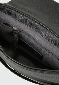 Wnętrze czarnej skórzanej torby z teksturowanym materiałem, zawierające kieszeń na zamek błyskawiczny i szare wykończenie z tkaniny. Prosty, funkcjonalny design do organizacji.