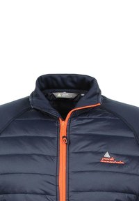 Veste matelassée marine avec fermeture éclair et accents orange. Présente une texture matelassée, un col haut et un logo sur la zone de la poitrine.