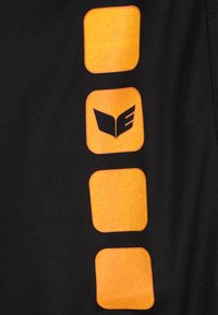 Zwarte stoffen sectie met drie getextureerde oranje vierkante accenten en een zwart logo-ontwerp. Het oppervlak lijkt ademend en glad.