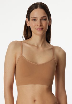 Tan bralette with thin straps, v-neckline, seamless design, and soft, stretchy fabric. Features a smooth, matte texture.