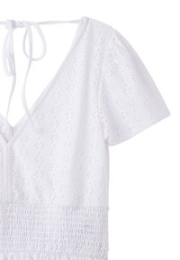 Top bianco a maniche corte con scollatura profonda a V. Tessuto texturizzato con piccoli buchi a occhio e dettagli arricciati in vita. Allacciatura sul retro.