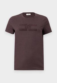 T-shirt en coton violet foncé à manches courtes, avec un design de logo texturé au centre. Col rond et tissu doux.