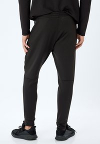 Sorte sporty joggers med en tætsiddende silhuet, elastisk talje og tapered manchetter, fremstillet af glat stof med minimale sømme.