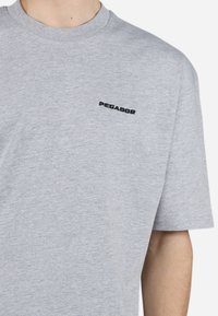 Sivá bavlnená tričko s okrúhlym výstrihom a krátkymi rukávmi. V prednej časti sa nachádza čierne vyšívané logo "PEGADOR" na ľavej hrudi. Hladká textura.