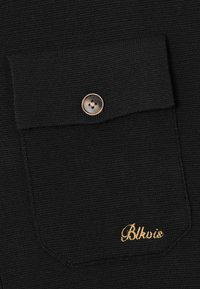 Zwart gebreid stoffen zak met klep en enkele bruine knop, met kleine gouden geborduurde tekst "Blkvis" in de rechterbenedenhoek.