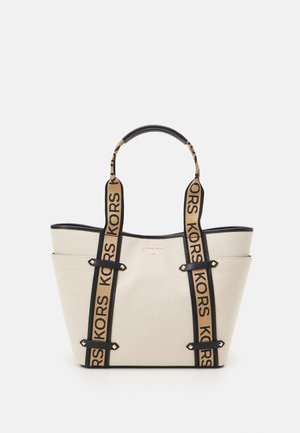 Beżowa torba na ramię z płótna z czarną lamówką i beżowymi uchwytami, z napisem "KORS", dwoma bocznymi kieszeniami i usztywnionym, prostokątnym kształtem.