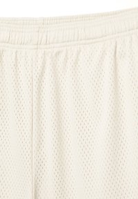 Shorts en tissu en maille de couleur crème clair, dotés d'une taille élastique, avec de petites perforations sur toute la surface pour une meilleure respirabilité.