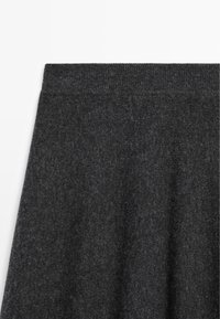 Donkergrijze gebreide rok met een gladde textuur en een brede tailleband. Subtiel patroon met een lichte glans, die zacht valt.