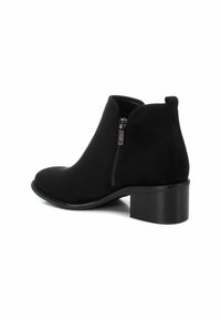 Botín negro de tobillo hecho de ante sintético, con cremallera lateral, puntera redondeada y un tacón bajo. Textura suave con acentos mínimos.