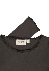 Camisa de algodón orgánico de color gris oscuro con un escote redondeado y un borde decorativo con forma de concha. La etiqueta dice "WHEAT" con información sobre la talla.
