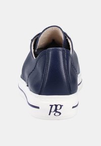 Zapatilla de cuero azul marino con suela blanca. La vista trasera muestra un interior acolchado y un logo en el talón. Textura suave y forma redondeada.