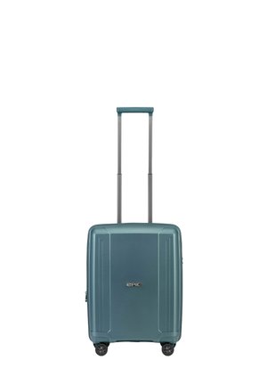 Valise rigide en teal avec une finition texturée, dotée d'une poignée rétractable, de quatre roues et d'un logo au centre.