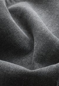 Dunkelgrauer Stoff mit weicher, strukturierter Webart, der subtile Licht- und Schatteneffekte zeigt und einen glatten, fließenden Fall aufweist.