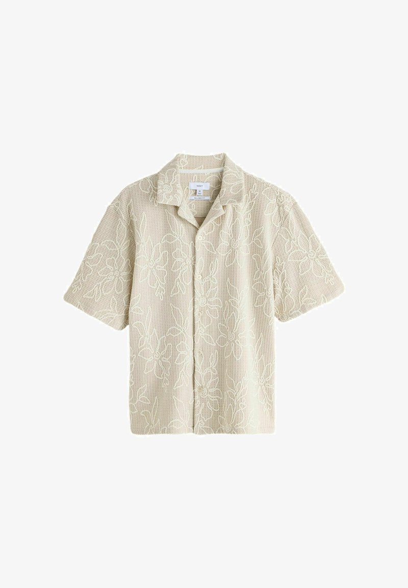 Camisa beige de manga corta con botones, tela texturizada y sutil bordado floral, con cuello abierto y etiqueta de tamaño mediano.