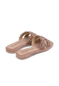 Sandales glissantes beiges avec deux larges sangles ornées de pierres précieuses roses et transparentes, présentant une texture en faux daim doux et une semelle plate.