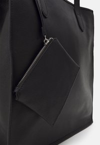 Sac fourre-tout en cuir noir avec une finition texturée, doté de deux poignées et d'une pochette zippée attachée en forme de losange.