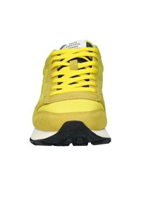 Sneaker giallo con tomaia in suede e mesh, punta tonda, suola in gomma nera e lacci gialli ben visibili. Presenta un'etichetta sulla linguetta.