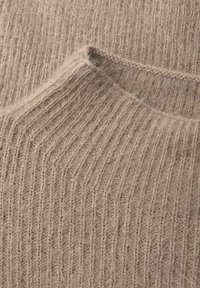 Beige rippenstrickstoff mit einer weichen Textur und einem kleinen, dezenten Taschen-Detail. Das Design weist vertikale Streifen und ein leichtes Aussehen auf.