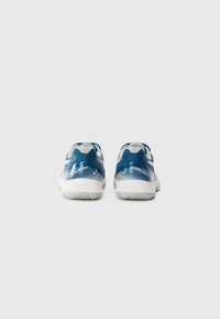 Des chaussures de sport bleu et blanc avec un design texturé, présentant un motif de vagues contrasté et une semelle en caoutchouc, vues de l'arrière.