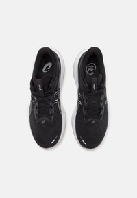 Scarpe da ginnastica nere con una tomaia in rete testurizzata, dettagli in bianco sulla suola intermedia, lacci piatti e logo sulla linguetta e sui lati.