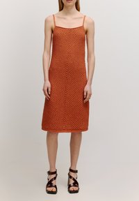 Roestkleurige, mouwloze jurk met een textuur en een chevronpatroon. Midi-lengte met smalle banden en een aansluitende silhouet.